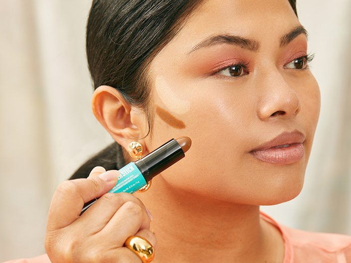 Person applying contour makeup to their cheekbone with NYX Professional Makeup Wonder Stick Contour and Highlighter Stick