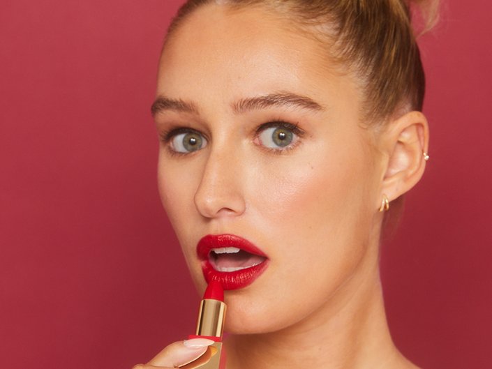 Person wearing red lipstick holding the lipstick up to her lips
