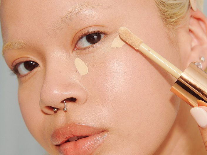 Close-up of a person applying concealer to their under-eye area
