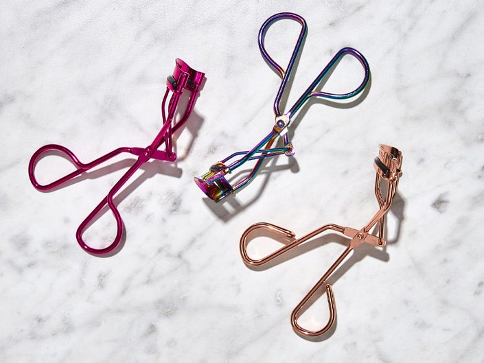 A picture of three eyelash curlers on a marble background
