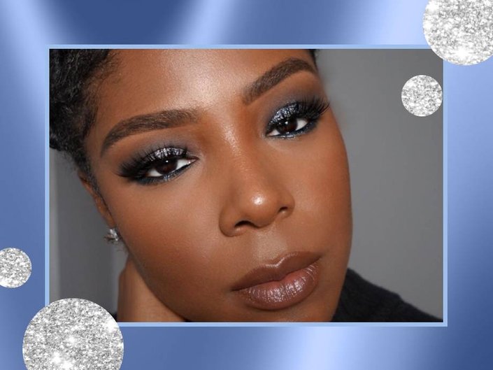 A young black woman wearing sparkly dark gray eyeshadow, long lashes, blush, and shimmery neutral lipstick