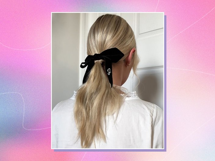 Back of the editor’s head with blonde hair in a low ponytail with a black velvet ribbon, collaged on a pink and purple graphic background