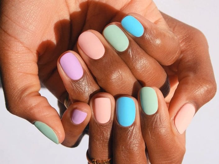 Hands of a person with pastel-colored nails, each painted a different color