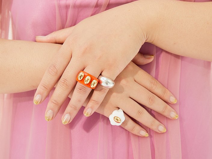 Close-up picture of a model's hands crossed in front of them, wearing multiple rings