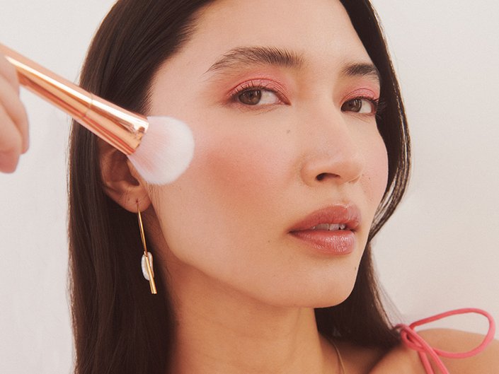 person applying blush to the apple of their cheek