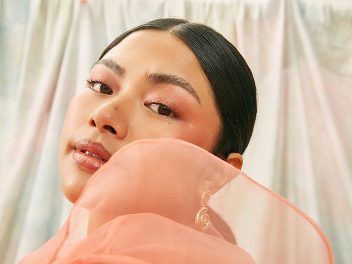 Picture of a model wearing pink eyeshadow and looking over their shoulder at the camera