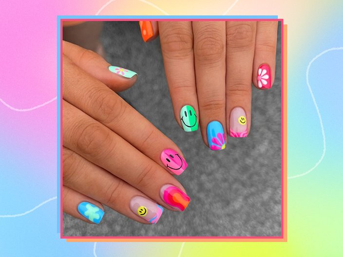 hands with brightly colored rainbow nails decorated with flowers and smiley faces