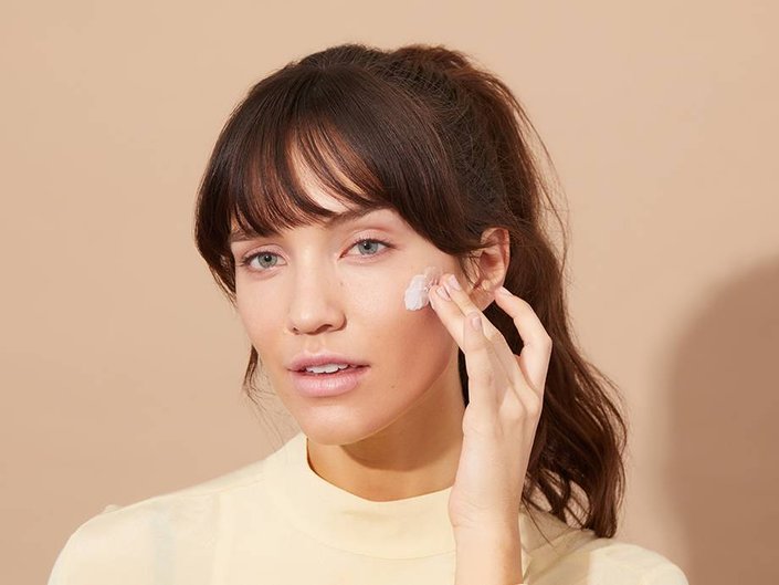 person applying moisturizer to cheek
